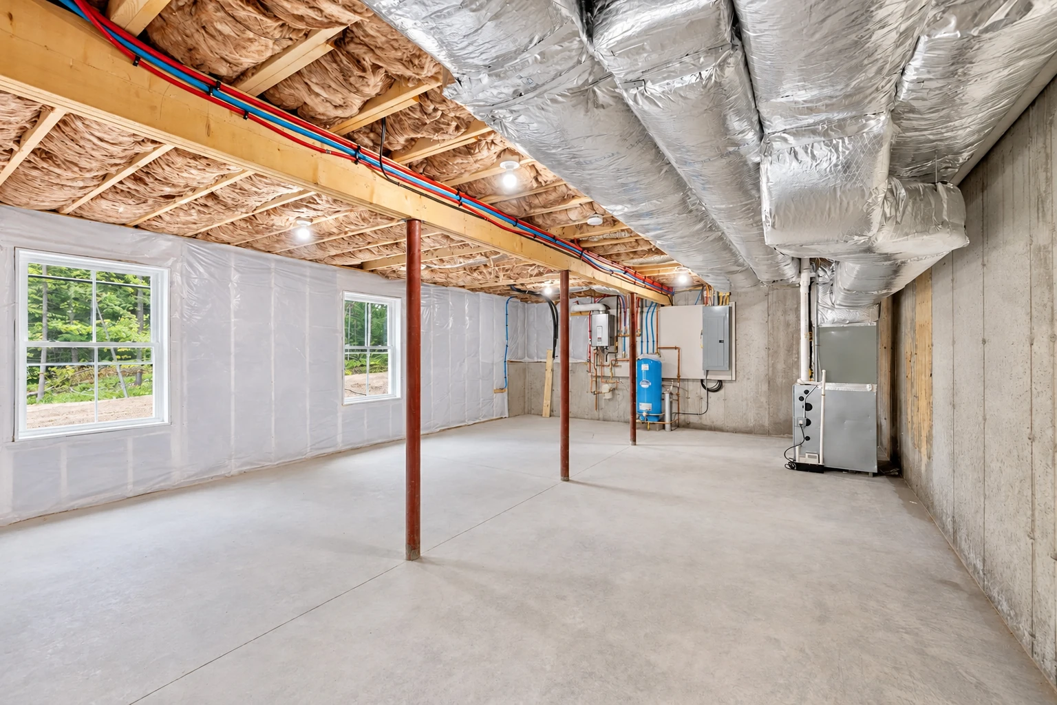 An unfinished basement has insulated ceiling joists, plastic-covered walls, exposed ducts and a concrete floor.